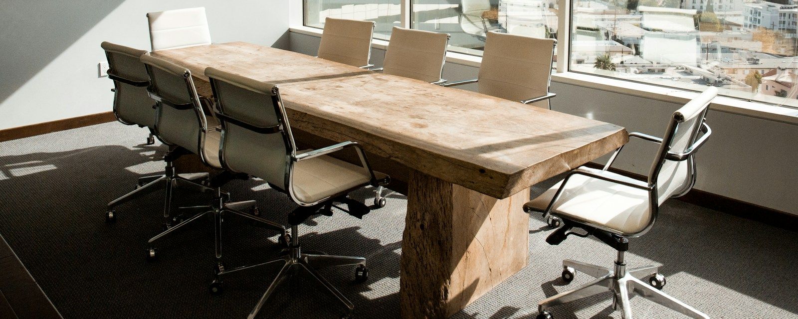 Sala de reuniones de un estudio profesional: mesa de madera maciza, sillas y un ventanal con luz natural